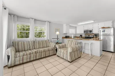 a living room with two couches and a kitchen at Island Time Bungalow in Panama City Beach