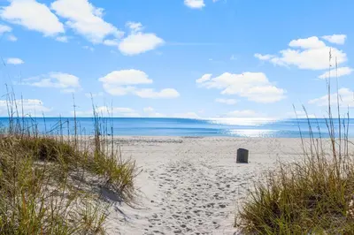 a beach with a trash can on the sand at Salt Life Bungalow in Panama City Beach