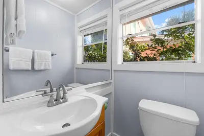 a white bathroom with a sink and a window at Salt Life Bungalow in Panama City Beach