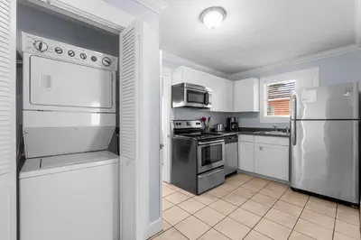 a kitchen with white cabinets and stainless steel appliances at Salt Life Bungalow in Panama City Beach