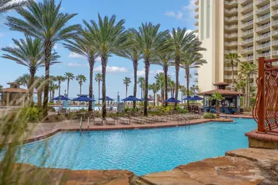 a pool at a resort with palm trees and blue umbrellas at Shores Of Panama #1926 in Panama City Beach