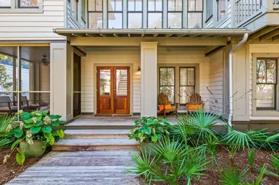 a front porch of a house with a wooden door at Captain Jack Cottage in Rosemary Beach