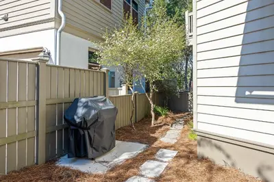 a trash can next to a fence next to a house at Captain Jack Cottage in Rosemary Beach