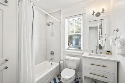 a white bathroom with a tub and a toilet and a sink at Captain Jack Cottage in Rosemary Beach