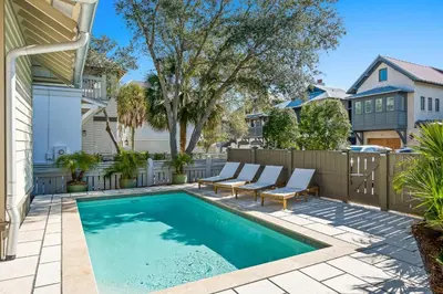 a swimming pool with two chairs and a fence at Captain Jack Cottage in Rosemary Beach