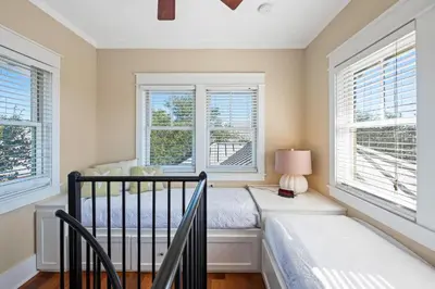 a bedroom with a bed and two windows at Captain Jack Cottage in Rosemary Beach
