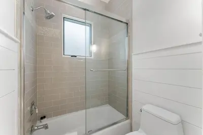 a bathroom with a shower and a toilet and a window at Chloe's Cottage and Carriage House in Rosemary Beach