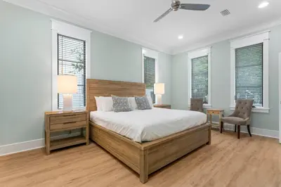 a bedroom with a bed and two chairs and windows at Chloe's Cottage and Carriage House in Rosemary Beach