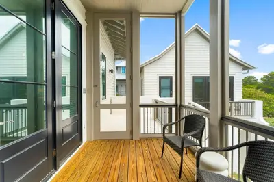 a screened porch with two chairs and windows at Chloe's Cottage and Carriage House in Rosemary Beach