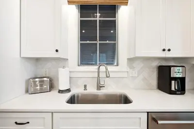 a kitchen with white cabinets and a sink at Rose Cottage in Rosemary Beach