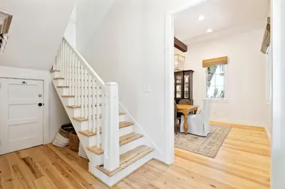 a staircase in a home with white walls and wooden floors at Rose Cottage in Rosemary Beach