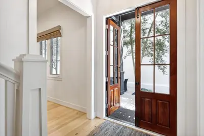 an open door in a white room with a wooden at Rose Cottage in Rosemary Beach