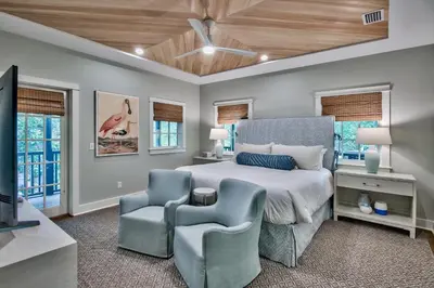 a bedroom with a bed and a chair and windows at Julia's Cottage in Rosemary Beach