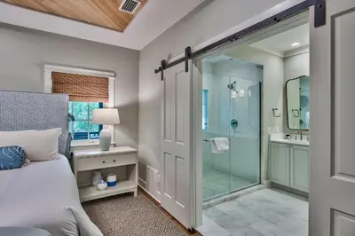 a bedroom with a glass shower and a bed at Julia's Cottage in Rosemary Beach