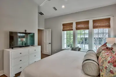 a bedroom with a bed and a tv and windows at Julia's Cottage in Rosemary Beach