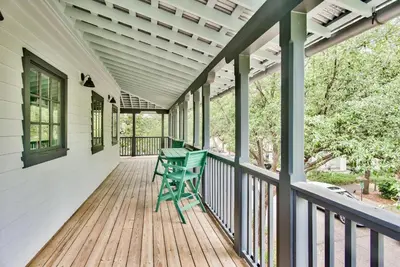 a porch with two green chairs on it at Julia's Cottage in Rosemary Beach