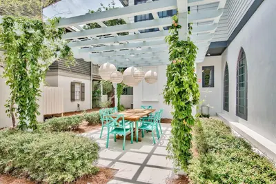 a patio with a wooden table and blue chairs at Julia's Cottage in Rosemary Beach