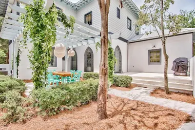 an exterior view of a white house with a table and chairs at Julia's Cottage in Rosemary Beach