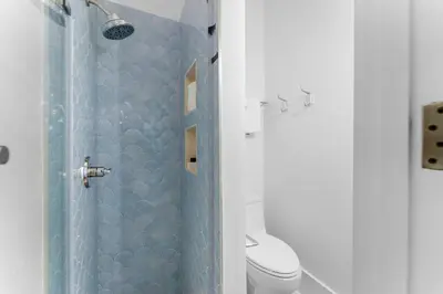 a bathroom with a blue shower with a toilet at Abaco Pearl Cottage in Rosemary Beach