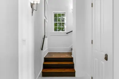 a hallway with white walls and stairs with a window at Abaco Pearl Cottage in Rosemary Beach