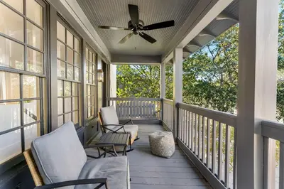 a screened porch with two chairs and a ceiling fan at Abaco Pearl Cottage in Rosemary Beach