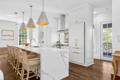 a kitchen with white cabinets and a large white island at Abaco Pearl Cottage in Rosemary Beach