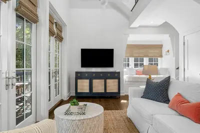 a living room with a white couch and a tv at Abaco Pearl Carriage House in Rosemary Beach