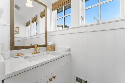 a white bathroom with a sink and a mirror at Abaco Pearl Carriage House in Rosemary Beach