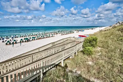 a beach with a bunch of umbrellas and the ocean at Abaco Pearl Carriage House in Rosemary Beach
