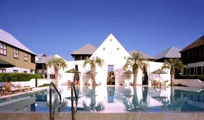 a resort with a swimming pool with palm trees and a building at Abaco Pearl Carriage House in Rosemary Beach