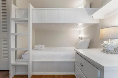 a bedroom with a white bunk bed and a desk at Julia's Carriage House in Rosemary Beach