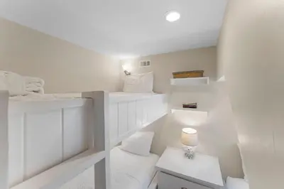a white room with two bunk beds and a table at Julia's Carriage House in Rosemary Beach