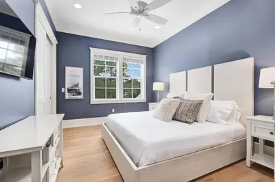a blue bedroom with a large bed and a window at Chalet by the Sea in Santa Rosa Beach