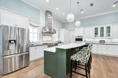 a large kitchen with white cabinets and a green island at Chalet by the Sea in Santa Rosa Beach