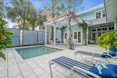 a patio with a pool and two chairs and a house at Chalet by the Sea in Santa Rosa Beach
