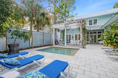 a patio with blue chairs and a swimming pool at Chalet by the Sea in Santa Rosa Beach
