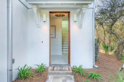 a front door of a white house with trees at Patience Cottage in Santa Rosa Beach