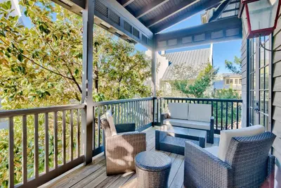 a porch with wicker chairs and a couch at Bella Cottage in Rosemary Beach