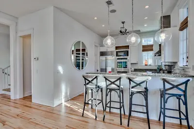 a kitchen with white cabinets and bar stools at Bella Cottage in Rosemary Beach