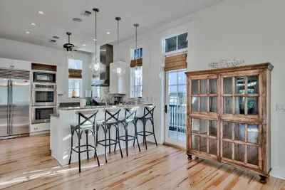 a kitchen with white walls and a wooden island with bar stools at Bella Cottage in Rosemary Beach