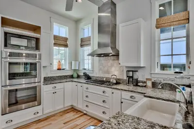 a kitchen with white cabinets and granite counter tops at Bella Cottage in Rosemary Beach
