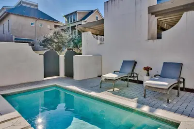a patio with two chairs and a swimming pool at Bella Cottage in Rosemary Beach