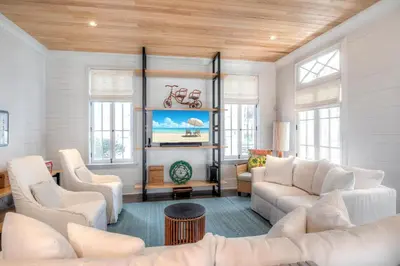 a living room with white furniture and wooden ceilings at Gates Cottage in Rosemary Beach