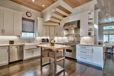 a kitchen with white cabinets and a wooden ceiling at Gates Cottage in Rosemary Beach
