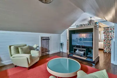 a living room with a tv and a couch and a table at Gates Cottage in Rosemary Beach