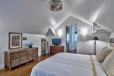 a bedroom with a white bed and a television at Gates Cottage in Rosemary Beach