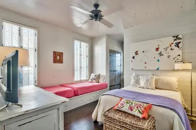 a bedroom with a bed and a flat screen tv at Gates Cottage in Rosemary Beach