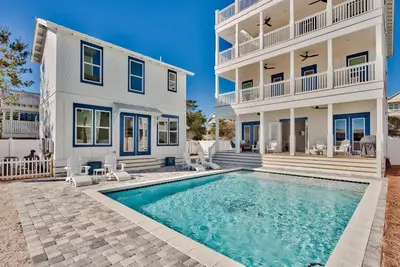a home with a swimming pool in front of a building at Gilligan's Island in Inlet Beach