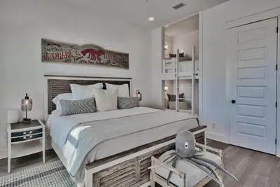 a white bedroom with a large bed and a chair at Gilligan's Island in Inlet Beach