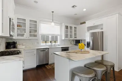 a kitchen with white cabinets and a kitchen island with stools at PTO Cottage in Rosemary Beach